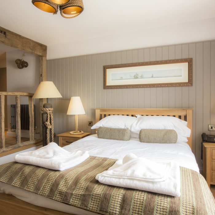 Rustic beams with olive and cream decor and and a large double bed.