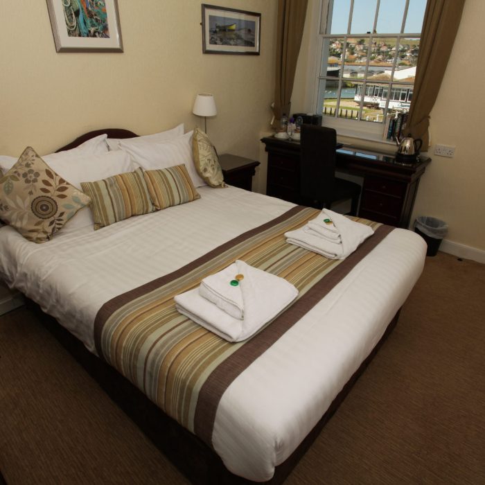 A double bedroom with striped cushions and bed runner. Views over West Bay from the window.
